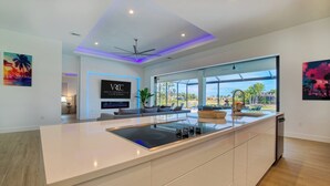 Una cocina moderna con una isla grande, comedor con vistas y ventilador de techo.