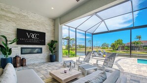 Un espacio exterior moderno con piscina, sillas de descanso y un letrero de Vacation Rentals Cape Coral.