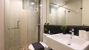 A modern bathroom with a glass-enclosed shower, a white sink, and a toilet.