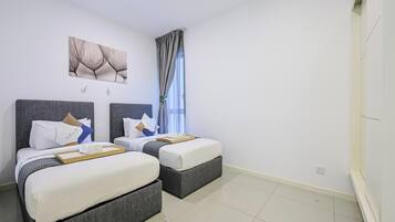 Een hotelkamer met twee bedden, een groot raam met gordijnen, een kunstwerk aan de muur en een schoon, betegeld vloer.