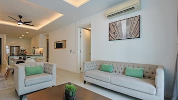 Una sala de estar moderna con un conjunto de sofás, una mesa de centro y un ventilador de techo.