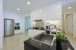 A modern kitchen with stainless steel appliances, a black countertop, and a sink. - The Shore Residence Melaka By I Housing (Malacca City)