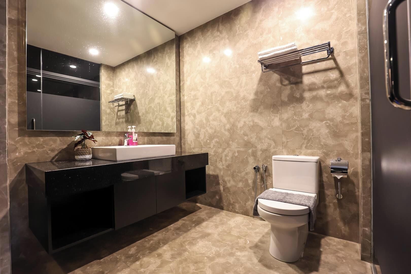 A modern bathroom with a black vanity, a white toilet, and a large mirror.