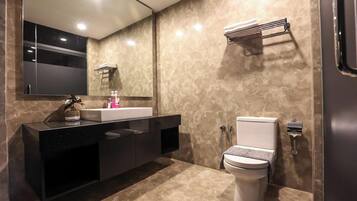 A modern bathroom with a black vanity, a white toilet, and a large mirror.