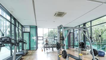 Un gimnasio con equipo cardiovascular, máquinas de pesas y amplias ventanas que ofrecen vistas al verdor.