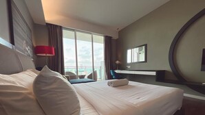 Hotellihuone, jossa on suuri sänky, työpöytä, tuoli ja näkymä kaupunkiin.