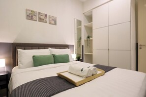 A hotel room with a bed, a nightstand, a wooden tray with towels, and a wardrobe. - The Shore Residence Melaka By I Housing (Malacca City)
