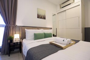 A hotel room with a bed, a nightstand with a lamp, a painting on the wall, and a wardrobe. - The Shore Residence Melaka By I Housing (Malacca City)