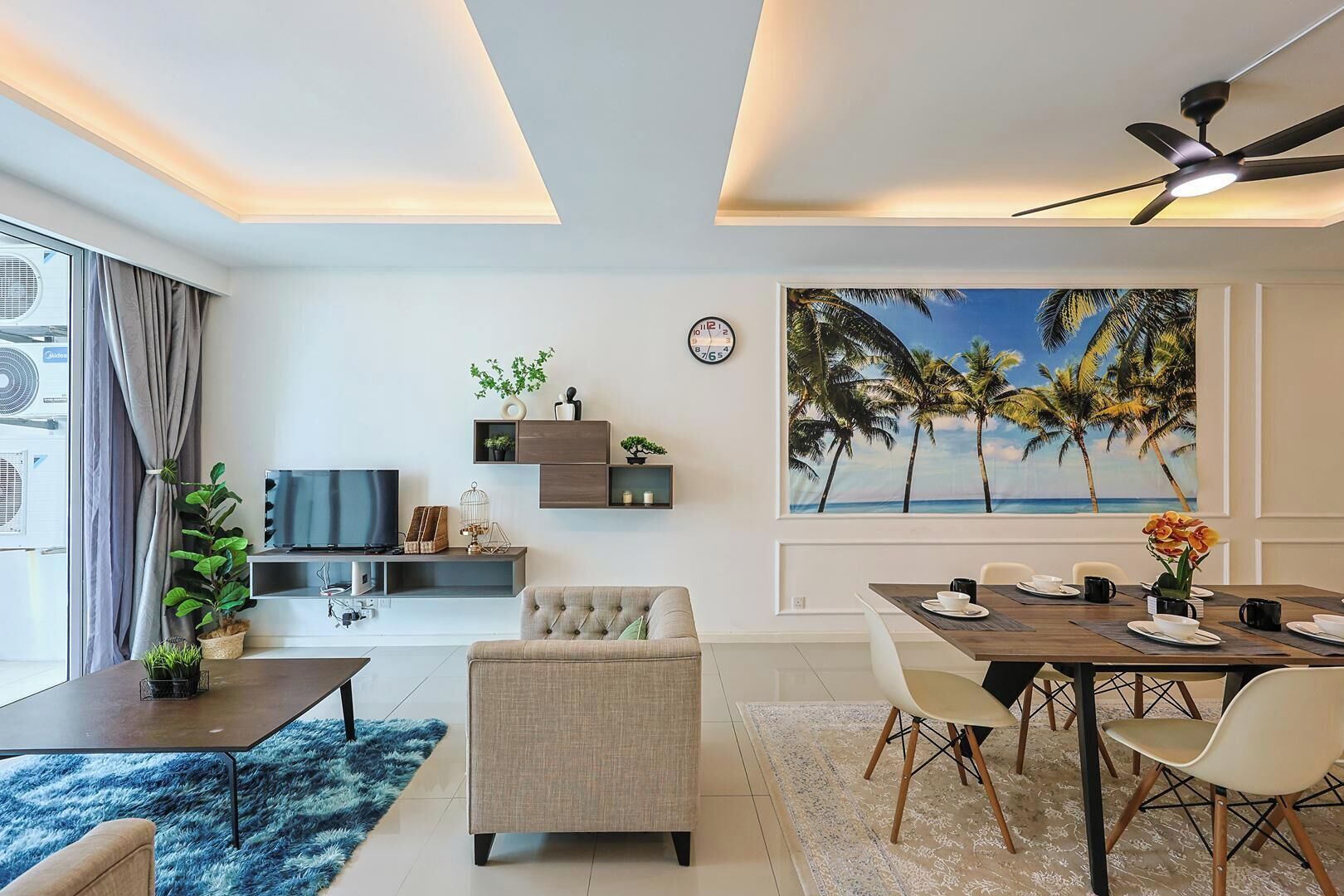 Una sala de estar moderna con un sofá, una mesa de comedor para cuatro personas, un televisor y un cuadro grande de palmeras.