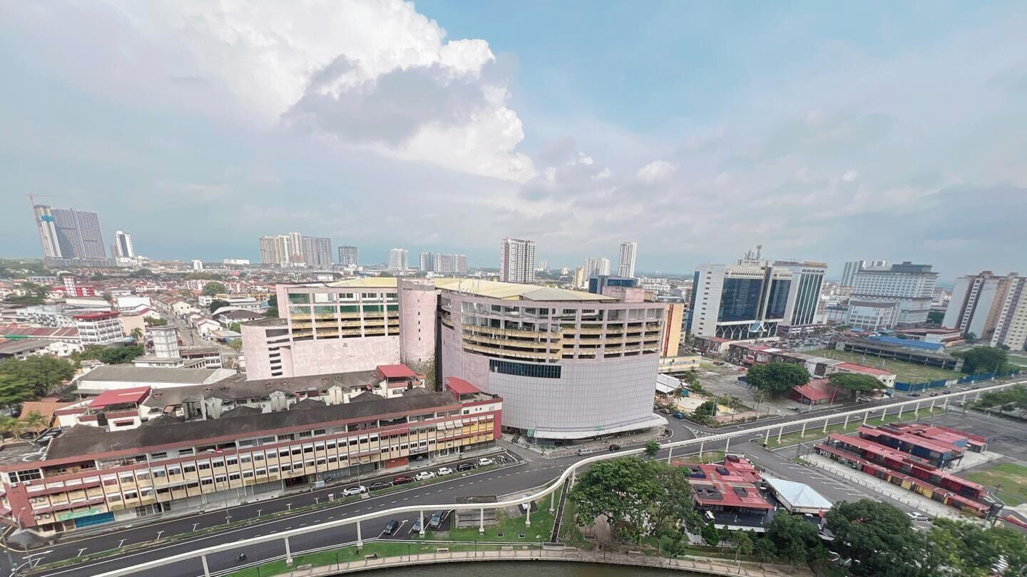 A cityscape with a prominent curved building, a multi-story parking structure, and a network of roads.