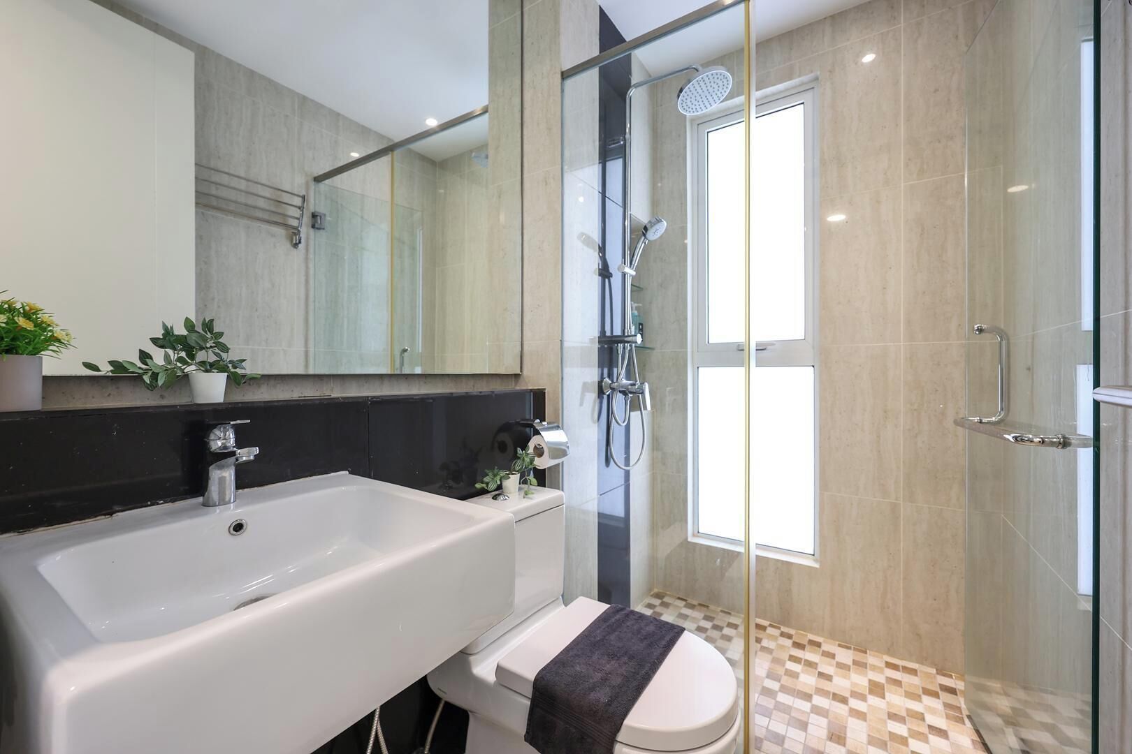 Ein modernes Badezimmer mit einer gläsernen Duschkabine, einer großen weißen Badewanne und einem WC mit Handtuch.