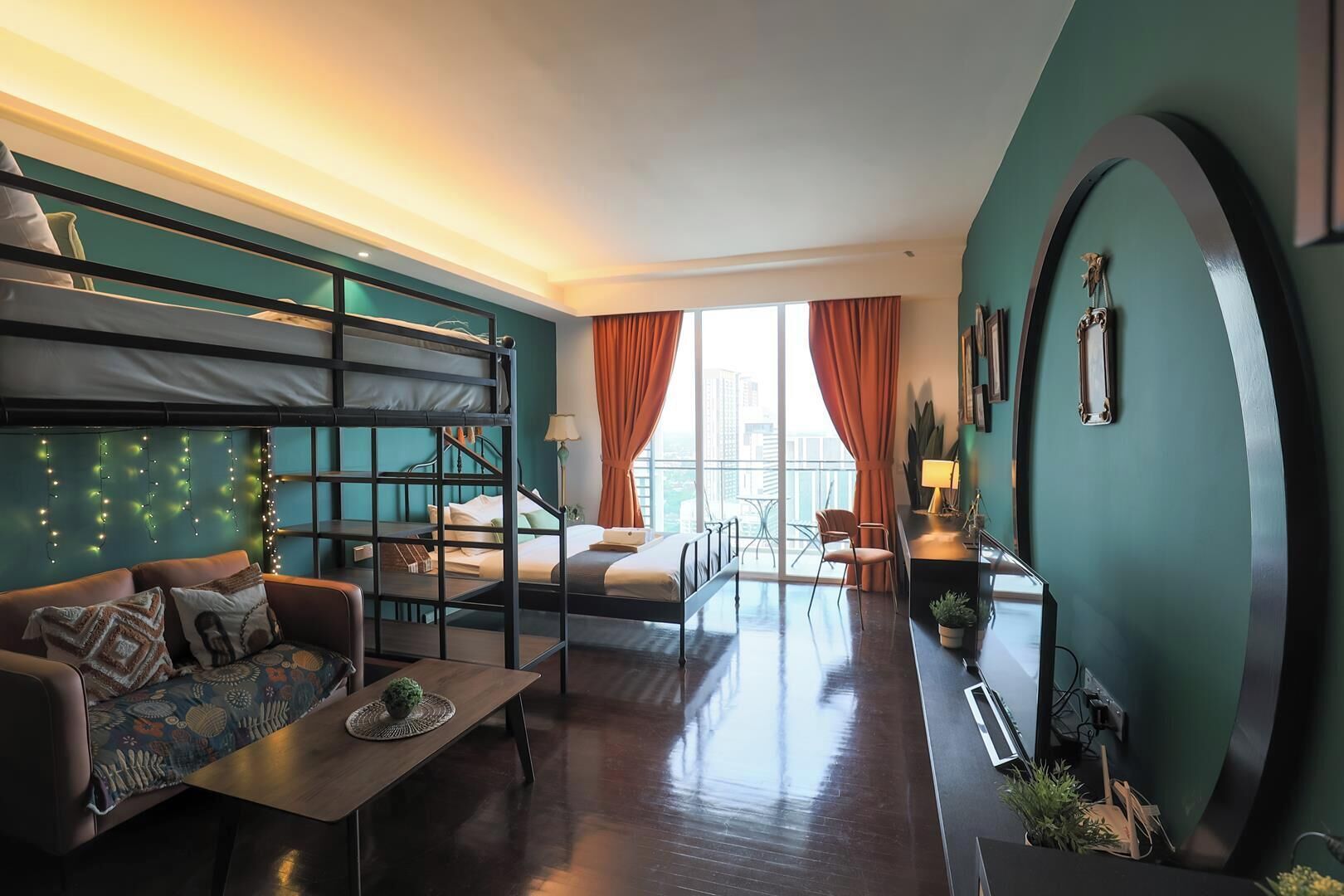 Een moderne hotelkamer met een stapelbed, een slaapbank, een bureau en uitzicht op de stad.