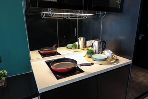 A kitchen with two induction cooktops, a range hood, and various kitchenware including a frying pan, a kettle, and a coffee pot. - The Shore Residence Melaka By I Housing (Malacca City)
