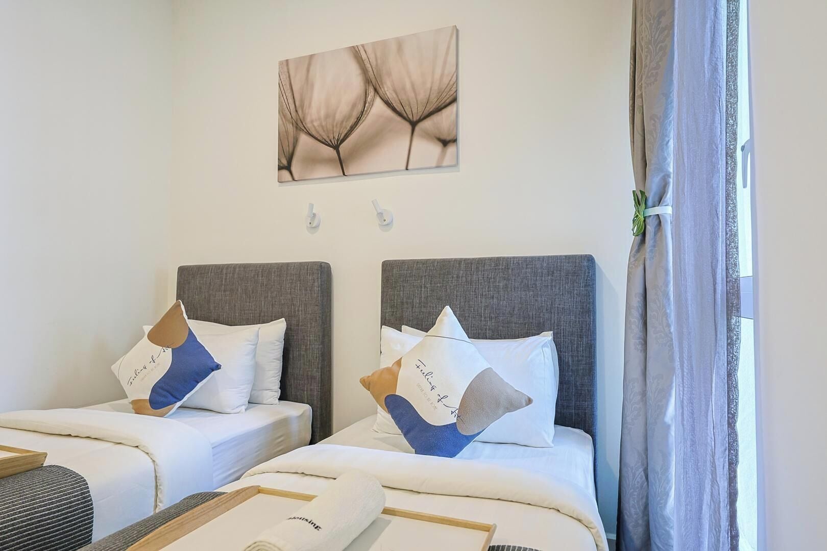 A hotel room with two beds, each with a headboard, pillows, and a wall-mounted artwork above.