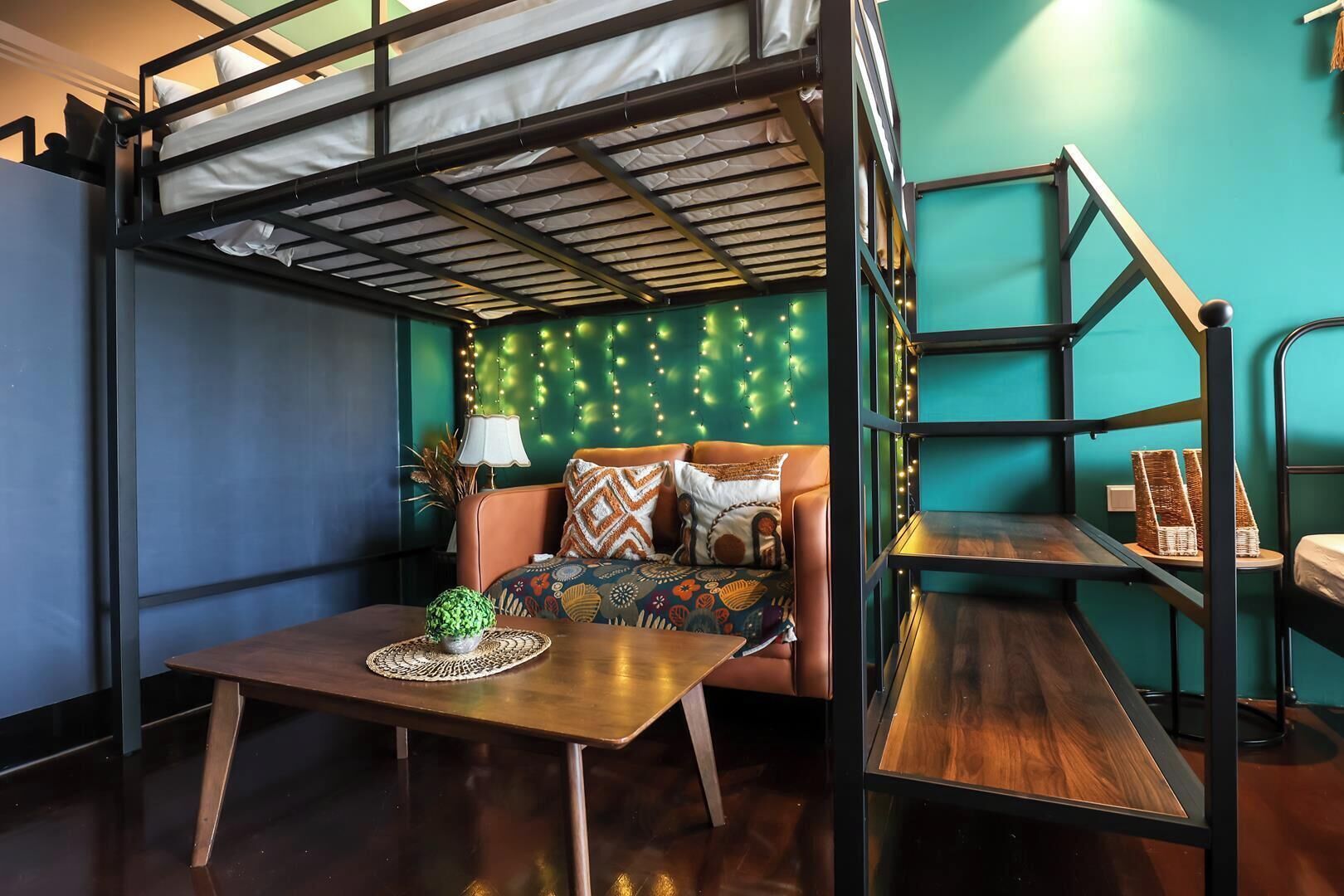 A bunk bed room with a sofa, a small table, and a lamp.