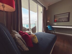 A modern hotel room with a large window, a sofa, a chair, and a desk. - The Shore Residence Melaka By I Housing (Malacca City)