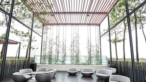 A covered outdoor seating area with wicker furniture and a view of the cityscape. - The Shore Residence Melaka By I Housing (Malacca City)