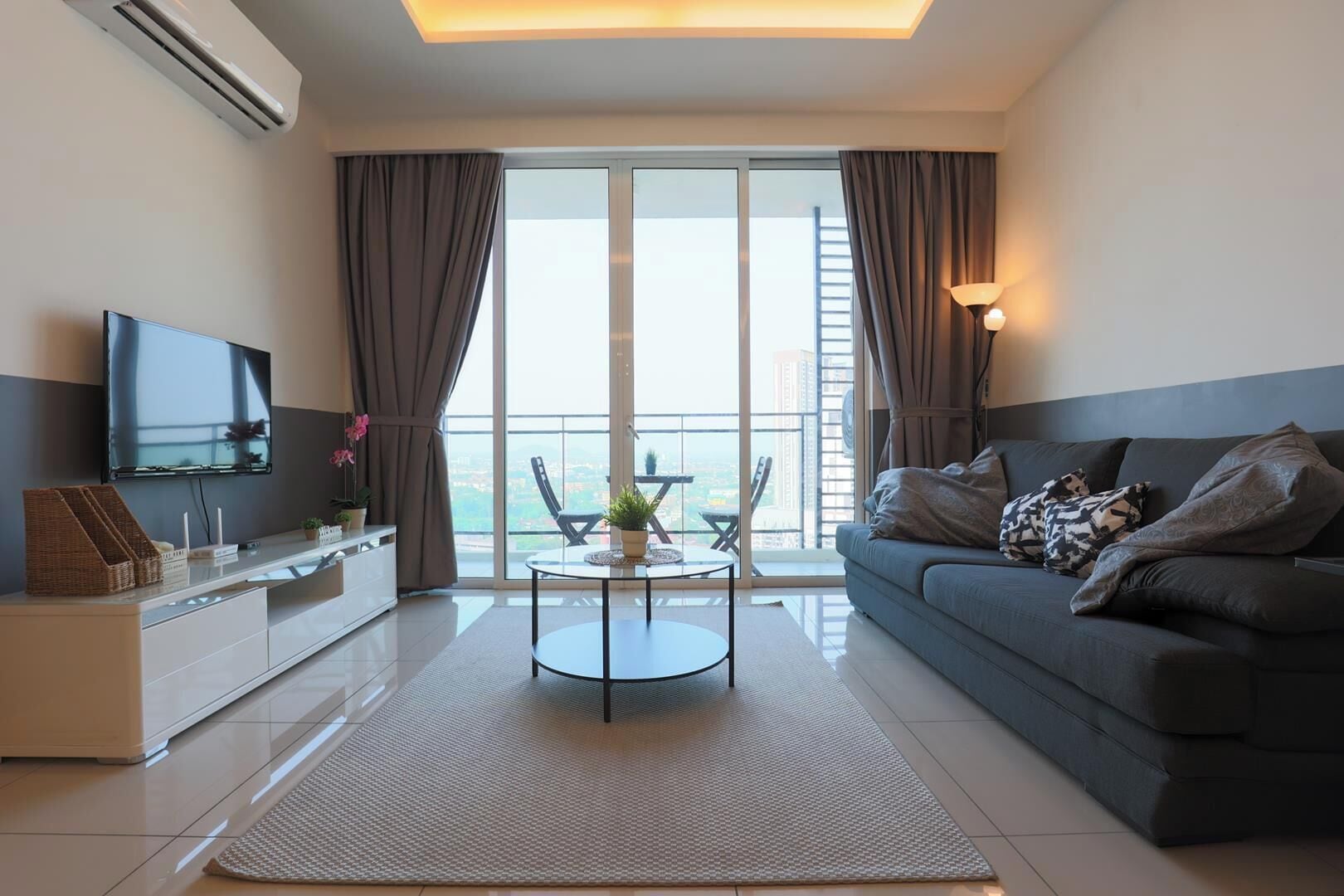 Een moderne woonkamer met een bank, een flatscreen televisie, een eettafel en een balkon met uitzicht.