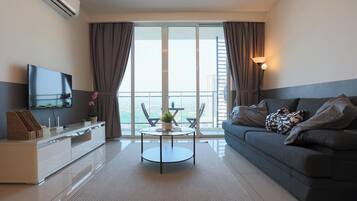 Een moderne woonkamer met een bank, een flatscreen televisie, een eettafel en een balkon met uitzicht.