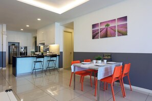 A modern kitchen with a central island, a dining area with red chairs, and a wall with three lavender field paintings.