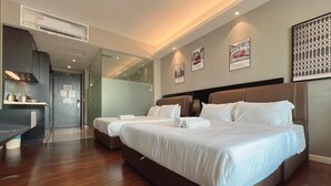 Moderni hotellihuone, jossa on suuri sänky, erillinen oleskelualue ja pieni keittiönurkkaus.