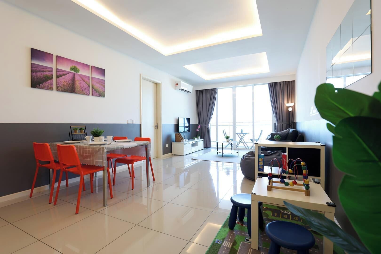 A modern living room with a dining area, a TV, and a large window.