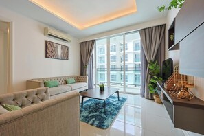 A modern living room with a sofa, a coffee table, and a TV on a stand. - The Shore Residence Melaka By I Housing (Malacca City)