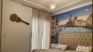 A bedroom with a bed, a guitar, a view of Venice, and a window with curtains. - Résidence nirvâna  (Sousse)