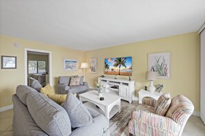 A living room with a sofa, armchairs, a coffee table, a TV, and artwork on the walls.