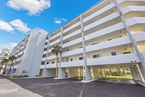 A multi-story parking garage with white walls and a clear sky.