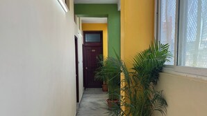 Un couloir aux murs jaune et vert, doté d’un sol en marbre et agrémenté de plantes en pot.