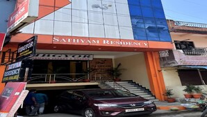 Un immeuble avec une enseigne indiquant « Sathyam Residency » et, en dessous, un magasin appelé « Vibgyor ».