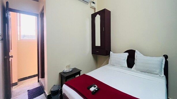 Une chambre d’hôtel équipée d’un lit, d’une armoire, d’une petite table, d’une poubelle et d’un appareil de climatisation.