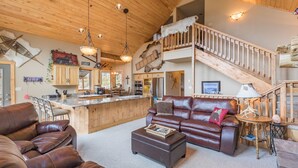 A spacious living area with a leather sofa, a coffee table, and a dining area with a kitchen in the background.