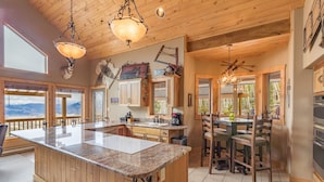 A spacious kitchen with wooden cabinetry, a large island, and a dining area with a view of the mountains.