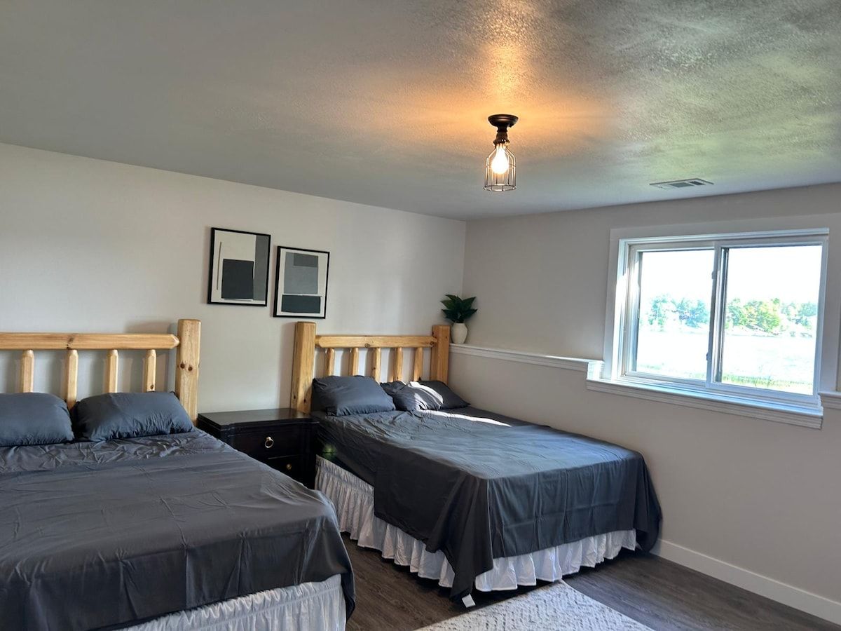A bedroom with two beds, a window, and a ceiling light fixture.