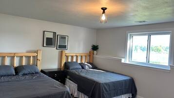 A bedroom with two beds, a window, and a ceiling light fixture.