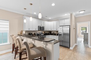 A modern kitchen with white cabinets, stainless steel appliances, and a central island with bar stools.