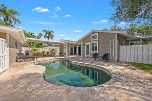 Un jardin avec une piscine, des chaises longues et un espace patio.