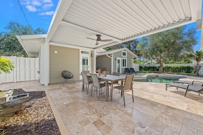 A covered patio with a pool, outdoor seating, and a dining area.