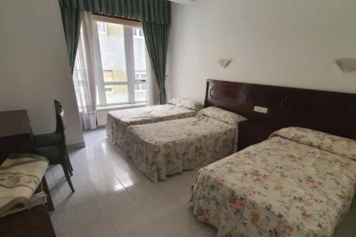 A room with two single beds, a desk, and a chair.