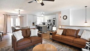 A modern living room with two brown leather sofas, a wooden coffee table, and a patterned rug.