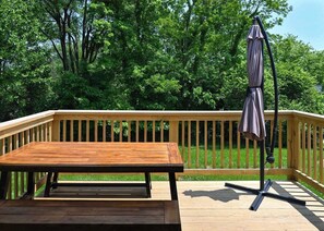 Una terraza de madera con una mesa y un paraguas.