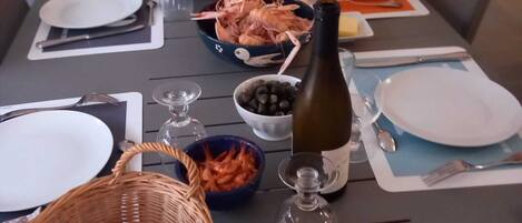 A dining table set with plates, cutlery, glasses, and food including bread and seafood.