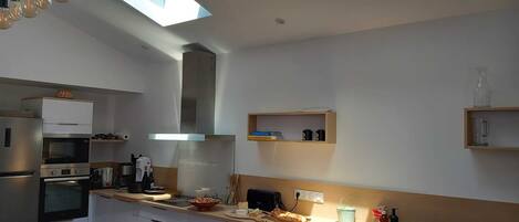 A modern kitchen with skylights, built-in appliances, and a minimalist design.