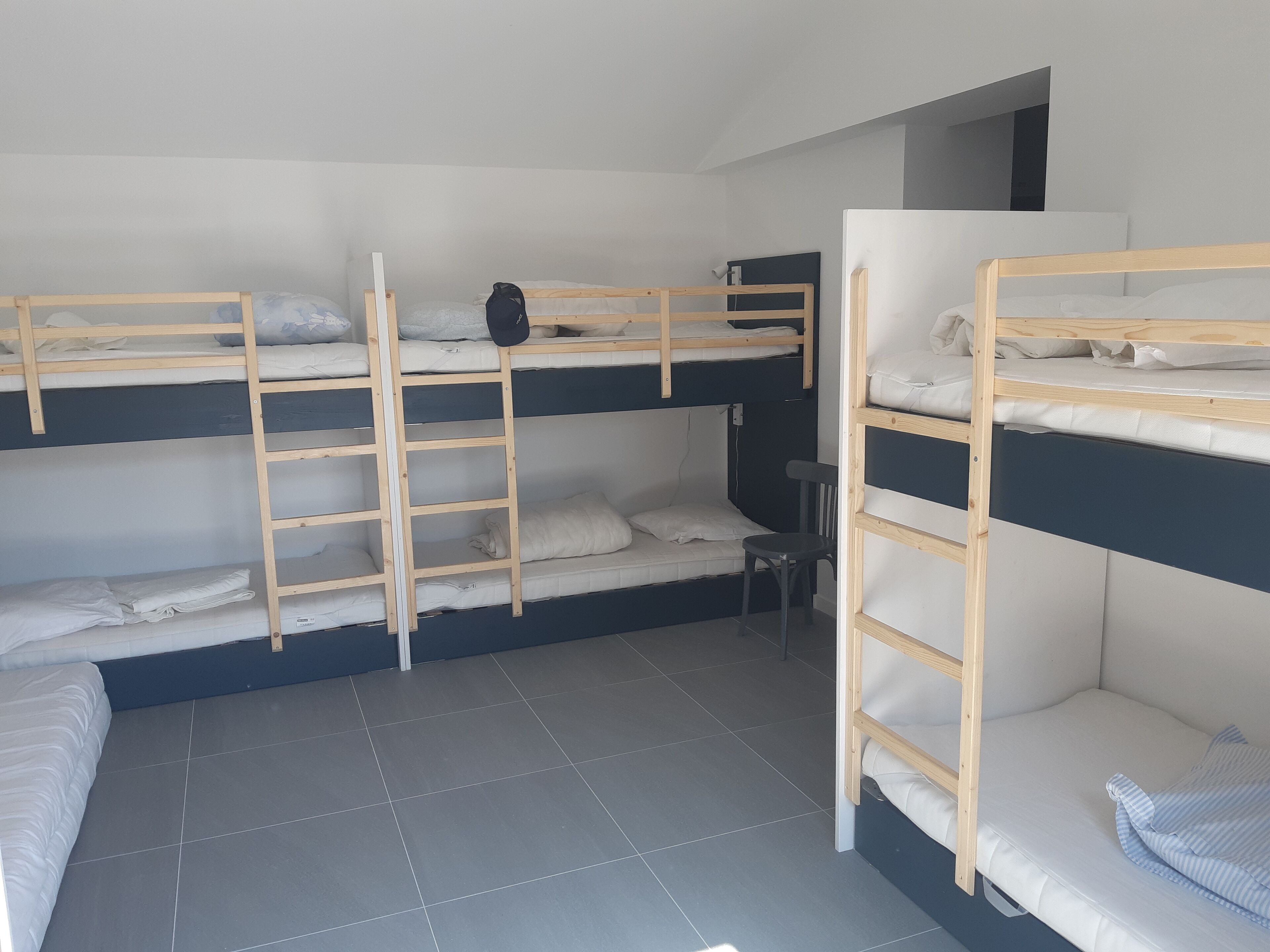 Um quarto de dormitório com beliches, uma escrivaninha pequena e uma cadeira.