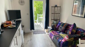 A compact living space with a kitchenette, a colorful sofa, a dining table, and a view through a glass door. - Studio Annie is the most relaxing place to stay  with free off road parking (Worthing)