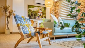 A modern living room with a wooden armchair, a light blue sofa, and a small table with a plant.