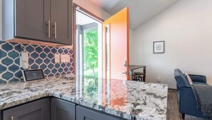 Una cocina moderna con gabinetes oscuros, encimera de mármol y una tableta sobre la encimera.