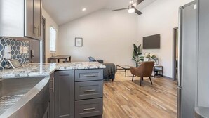 Una cocina moderna con armarios oscuros, encimera de mármol y ventilador de techo.